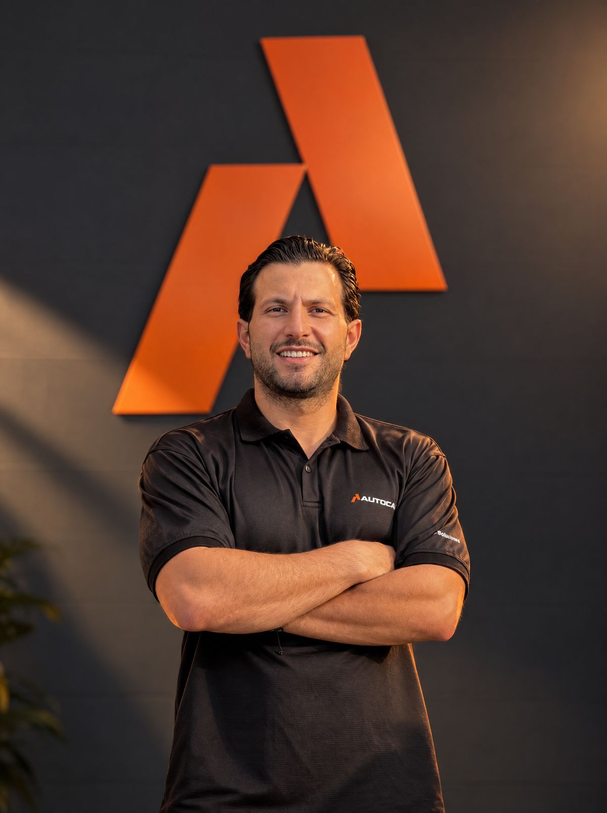 Antony Frech, de brazos cruzados frente al logo naranja de AUTOCA